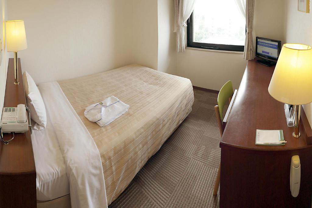 Postel nebo postele na pokoji v ubytování Kumegawa Wing Hotel