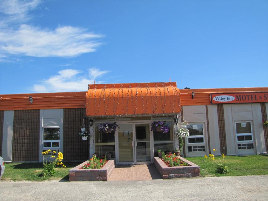 a building with flowers in front of a store at Valley Inn Motel in Sudbury