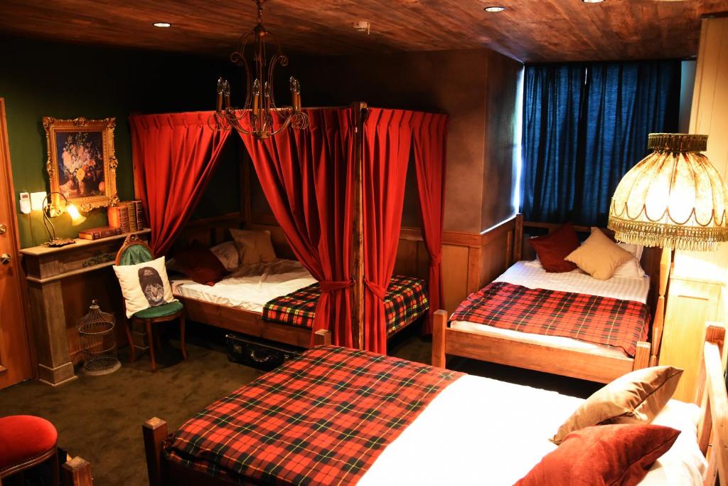 a bedroom with two beds and red curtains at Expected Inn in Fukuoka