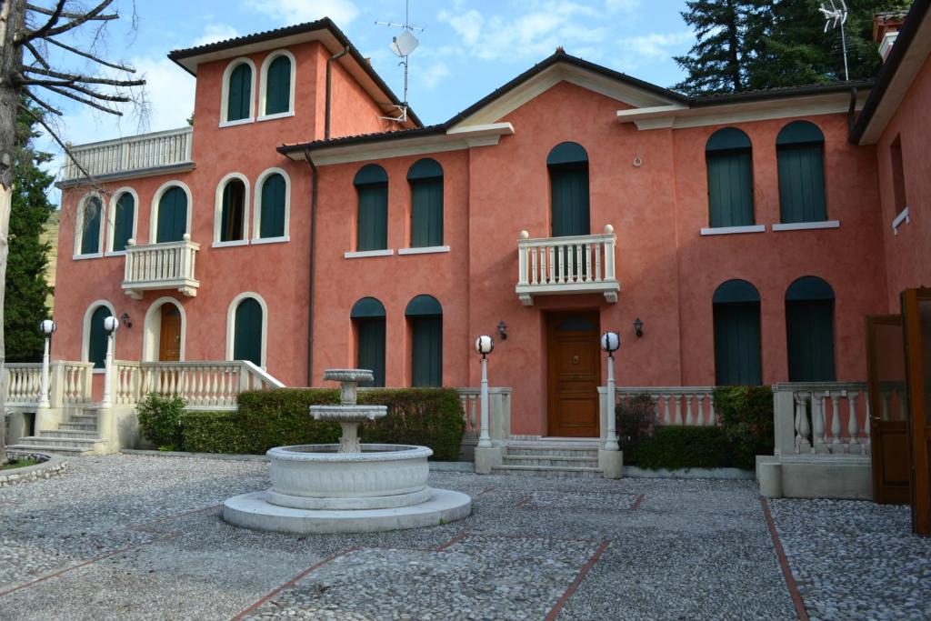duży czerwony budynek z fontanną przed nim w obiekcie B&B Villa Carli w mieście Caneva