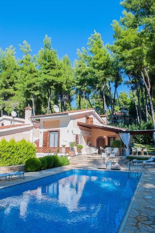 a large swimming pool in front of a house at Naftilos Villa Sani with private Pool in Sani Beach