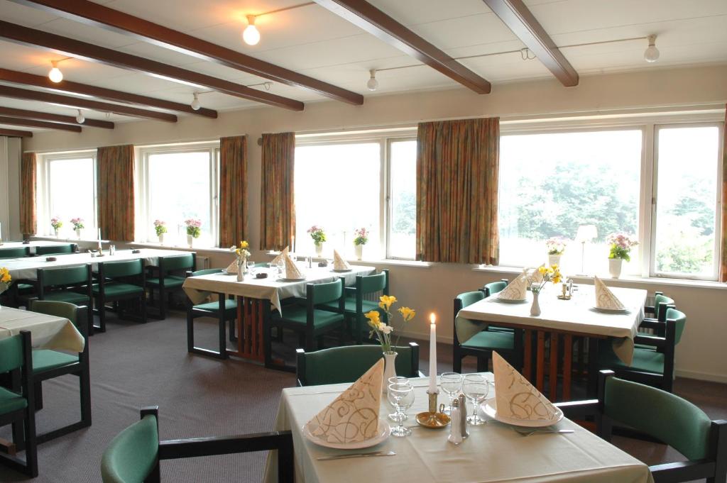 a restaurant with tables and green chairs and windows at Medio Apartments in Fredericia