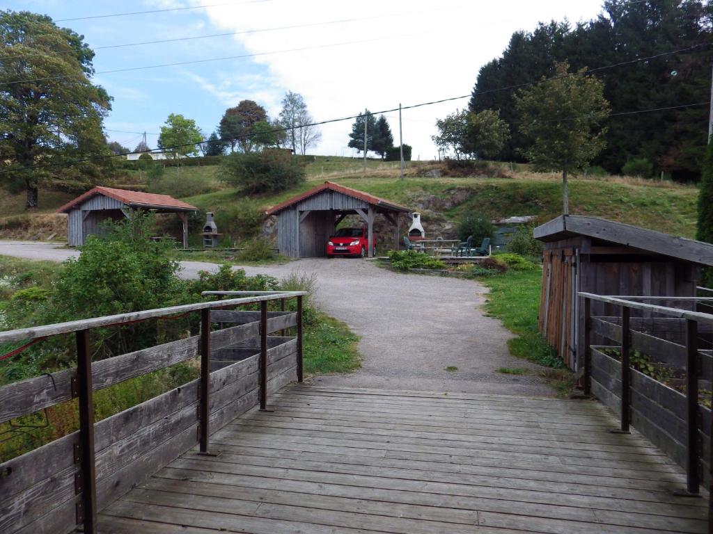 a wooden bridge leading to a barn with a red car at gites Les Bleuets in Vagney