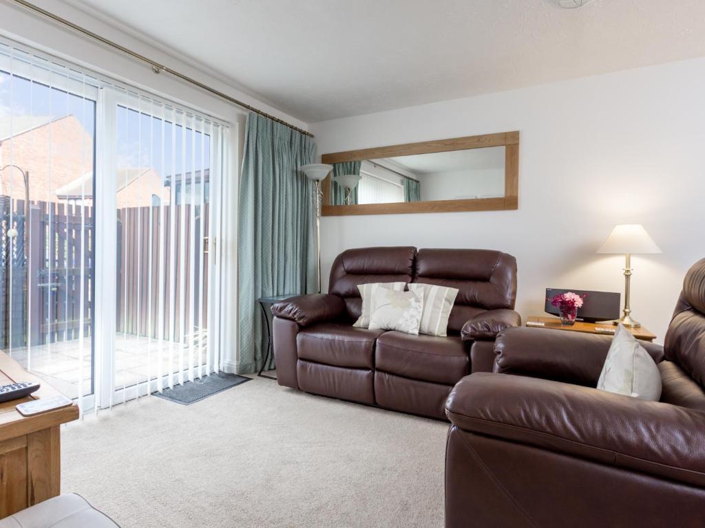 uma sala de estar com um sofá de couro e uma varanda em Sandpiper em Poole
