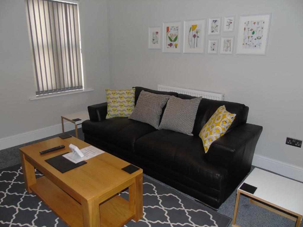 uma sala de estar com um sofá preto e uma mesa de centro em Jeffersons Hotel & Serviced Apartments - The Steel Works em Barrow in Furness