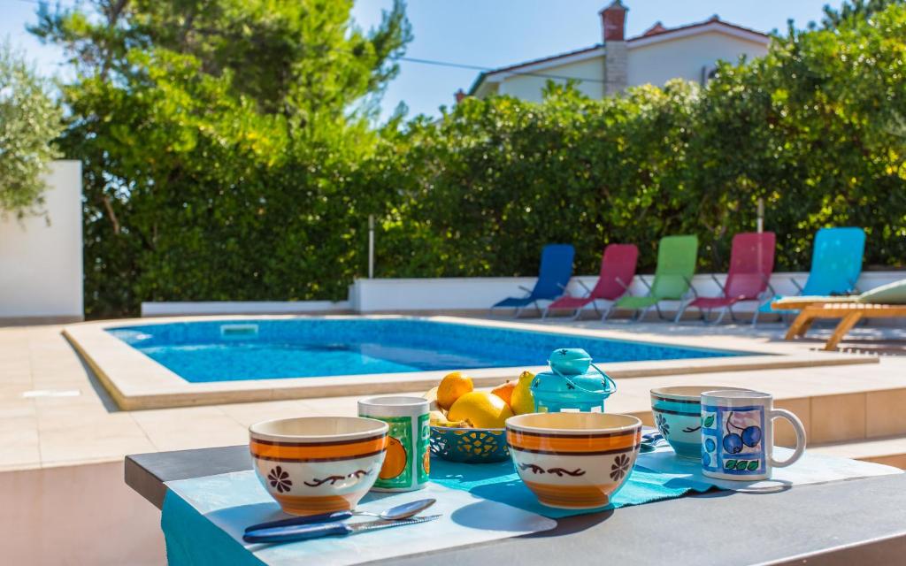 a table with cups and fruit on it next to a pool at Apartments Zeljko B in Šilo