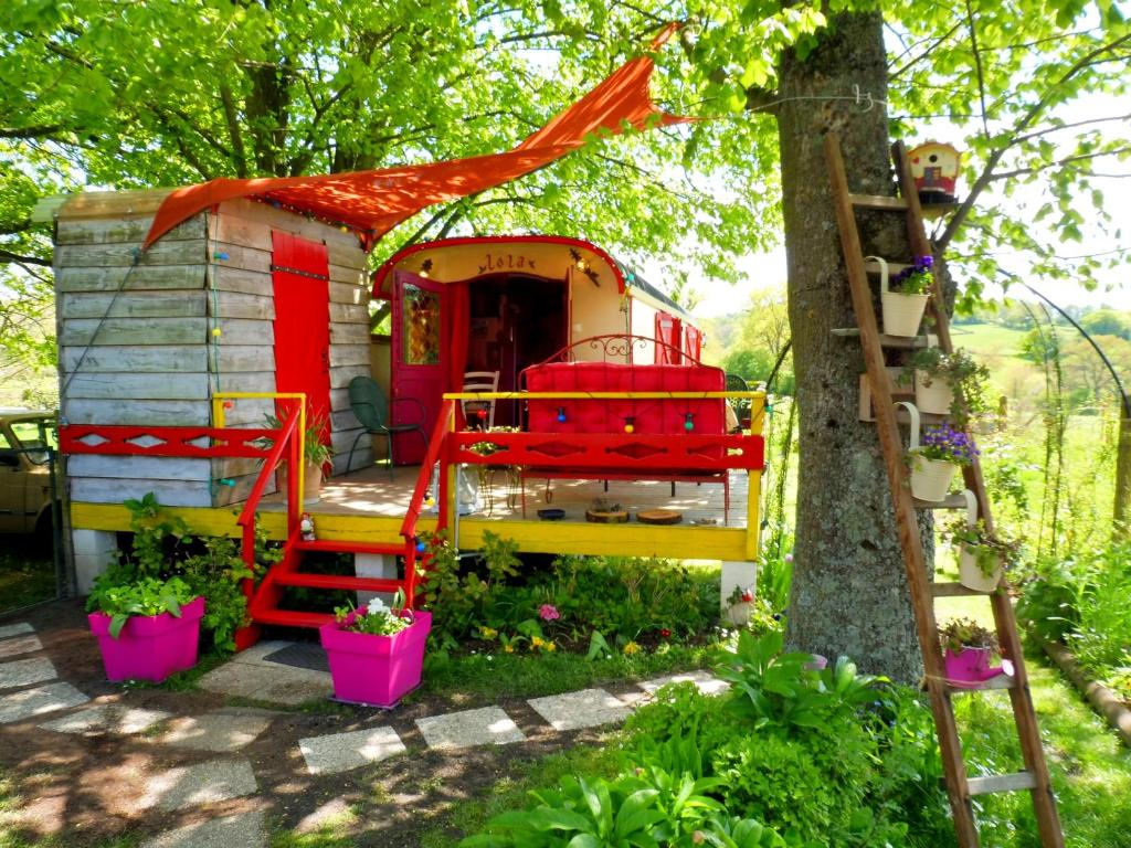 a play house with a red roof and a ladder at La Roulotte De Lola - Chambre d'hôtes in La Celle