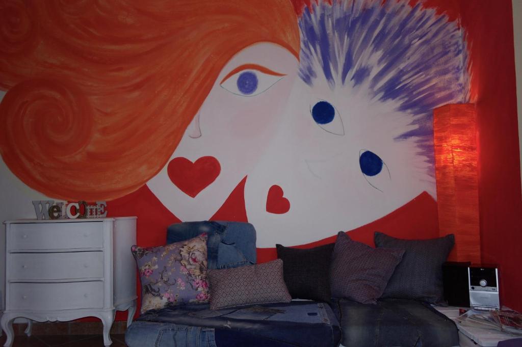 a living room with a wall with a painting of a hedgehog at Monolocale in residence con Piscina in Castagneto Carducci