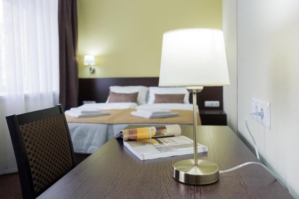 a table with a lamp and a bed in a room at Vash Hotel in Yekaterinburg