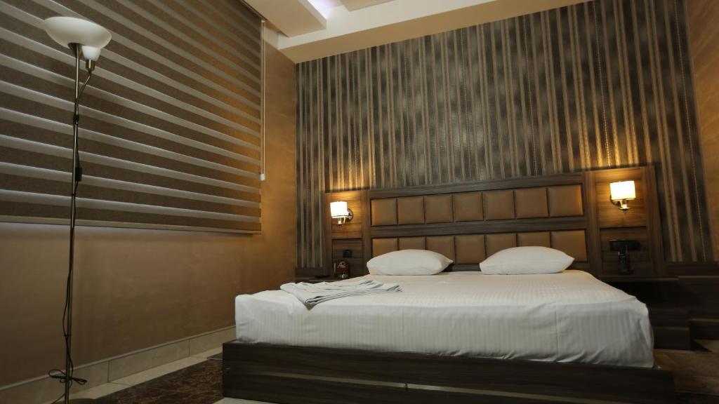 um quarto com uma cama com lençóis brancos e almofadas em Avan Plaza Hotel em Yerevan