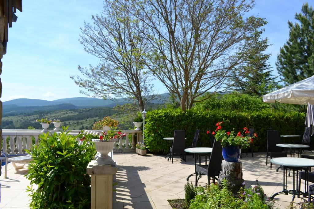 a patio with tables and chairs and mountains in the background at Logis Hôtel Le Vieil Amandier in Trigance