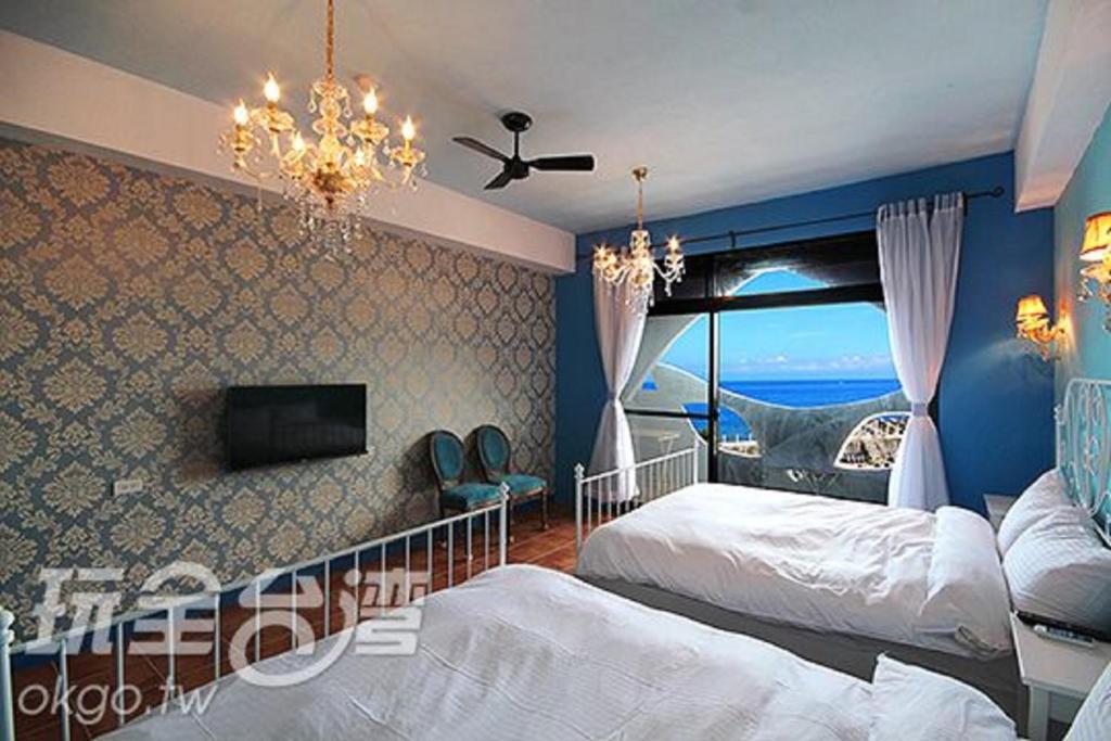 a bedroom with two beds and a flat screen tv at Moon's Diving House in Green Island