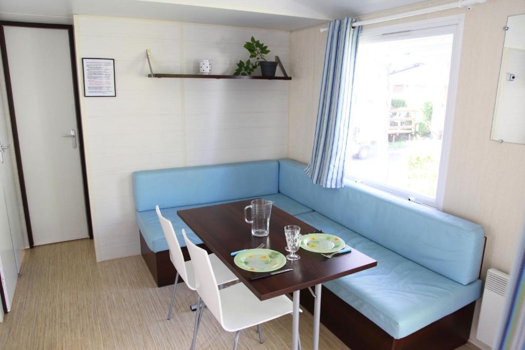 une salle à manger avec un canapé bleu et une table dans l&#39;établissement Camping La Clé des Champs, à Saint-Nectaire