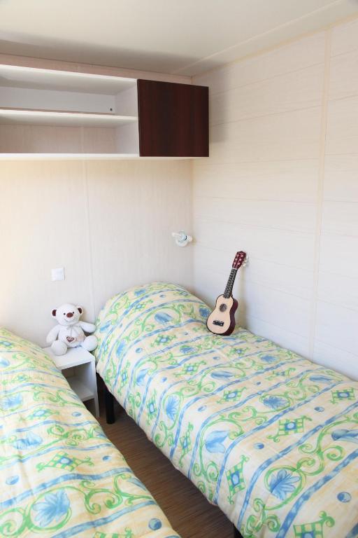- une chambre avec 2 lits et une guitare sur le mur dans l&#39;établissement Camping La Clé des Champs, à Saint-Nectaire