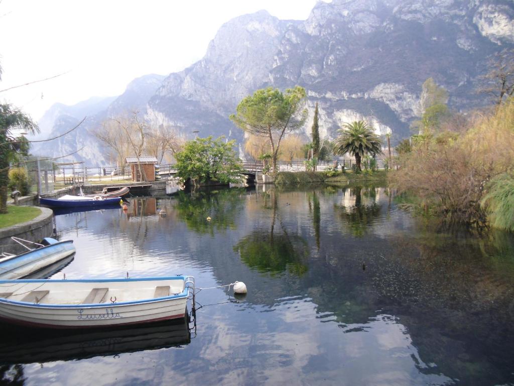 ein Boot in einem Fluss mit einem Berg im Hintergrund in der Unterkunft Garda Blu Apartment in Riva del Garda