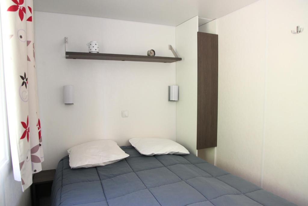 Cette petite chambre comprend un lit avec deux oreillers. dans l&#39;établissement Camping La Clé des Champs, à Saint-Nectaire