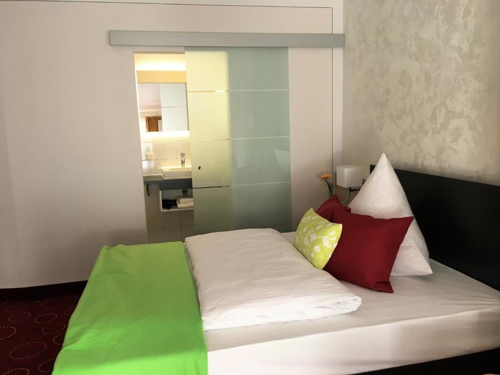 ein Zimmer mit einem Bett mit bunten Kissen darauf in der Unterkunft Waldgasthof St.Wolfgang in Sinning