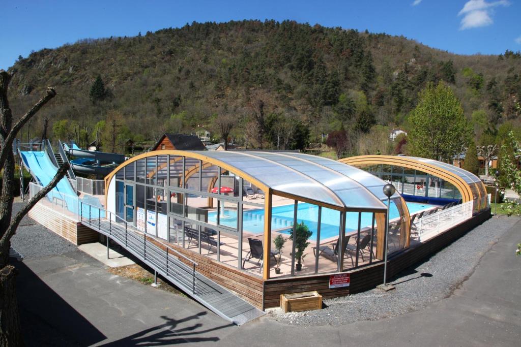 une maison sur un bateau avec une piscine dans l&#39;établissement Camping La Clé des Champs, à Saint-Nectaire