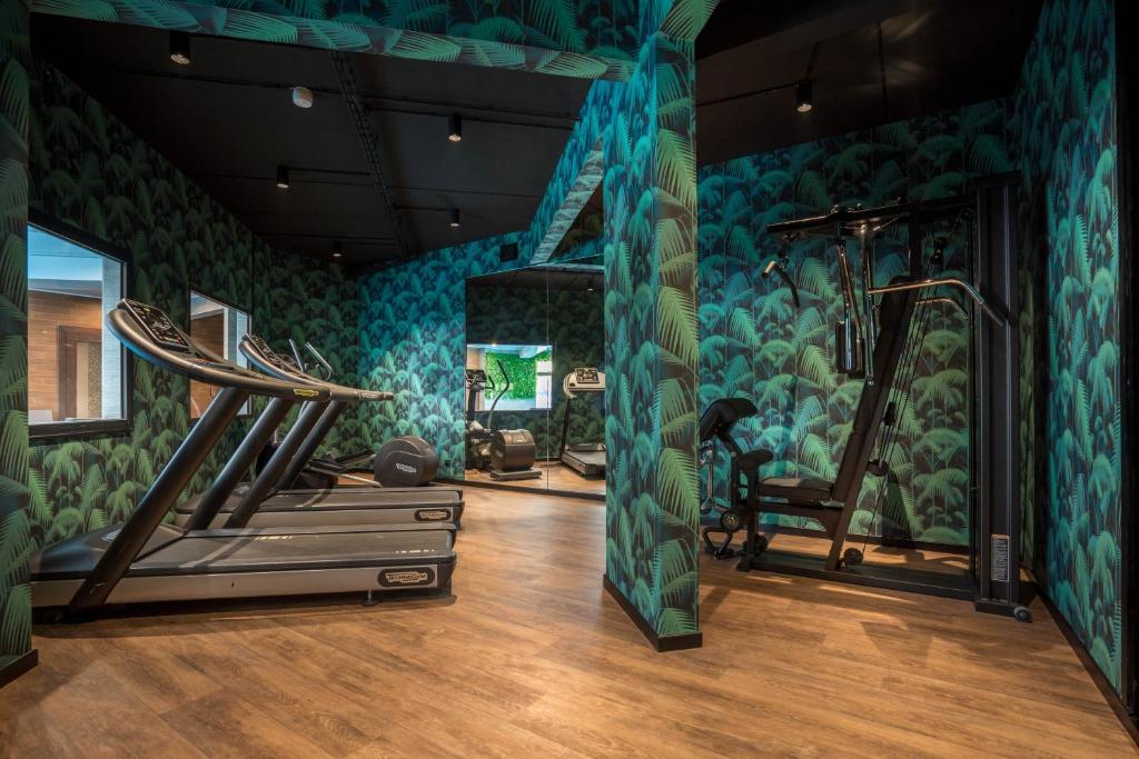 a room with a gym with a wall mural of plants at Best Western Plus Hostellerie Du Vallon in Trouville-sur-Mer