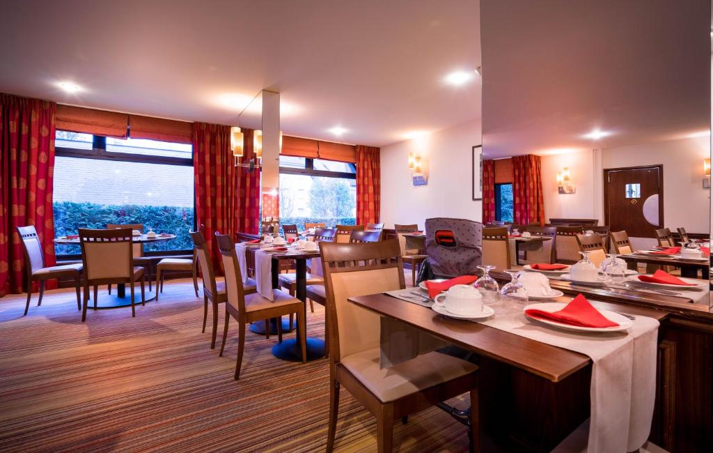 a restaurant with tables and chairs and a large window at Best Western Plus Hostellerie Du Vallon in Trouville-sur-Mer