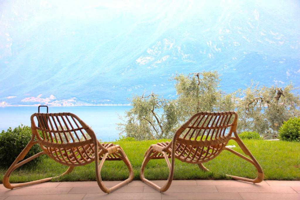 two benches sitting next to each other in front of the water at Oliveto in Limone sul Garda