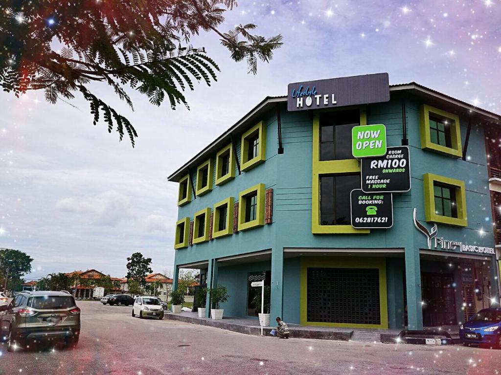 un edificio azul y amarillo con coches estacionados en un estacionamiento en Finess Basic Hotel, en Melaka