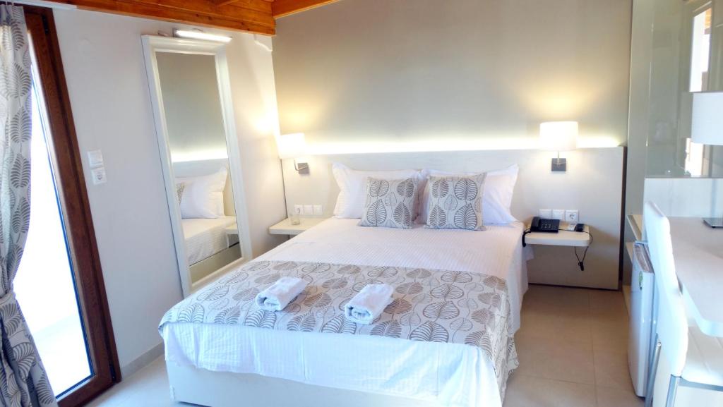een slaapkamer met een groot wit bed met kussens bij Athos Guest House Pansion in Ouranoupoli