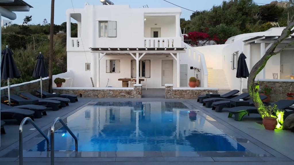 a swimming pool in front of a house with chairs and a building at Villa Varnali Small Boutique in Mikonos