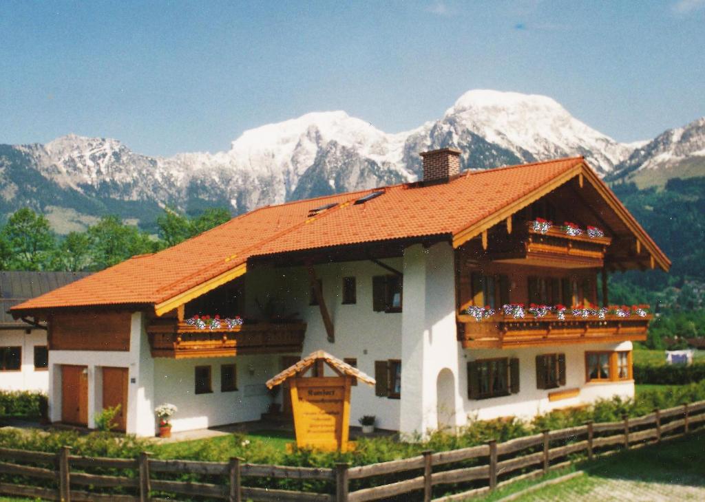 uma casa com um telhado laranja em frente às montanhas em Ferienwohnungen Haid em Schönau am Königssee