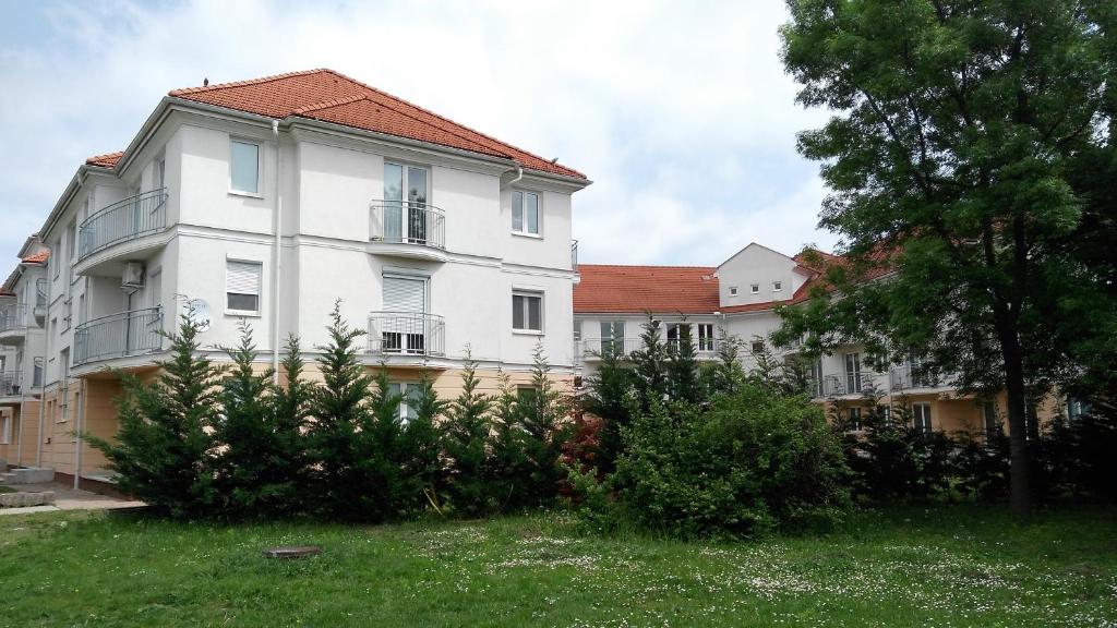 une grande maison blanche avec un arbre dans la cour dans l'établissement Thermal apartman, à Hajdúszoboszló