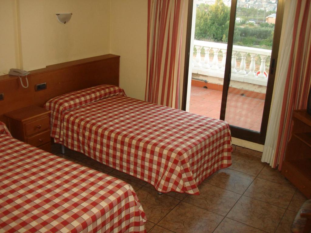 a hotel room with two beds and a window at Hostal Millán in Segorbe