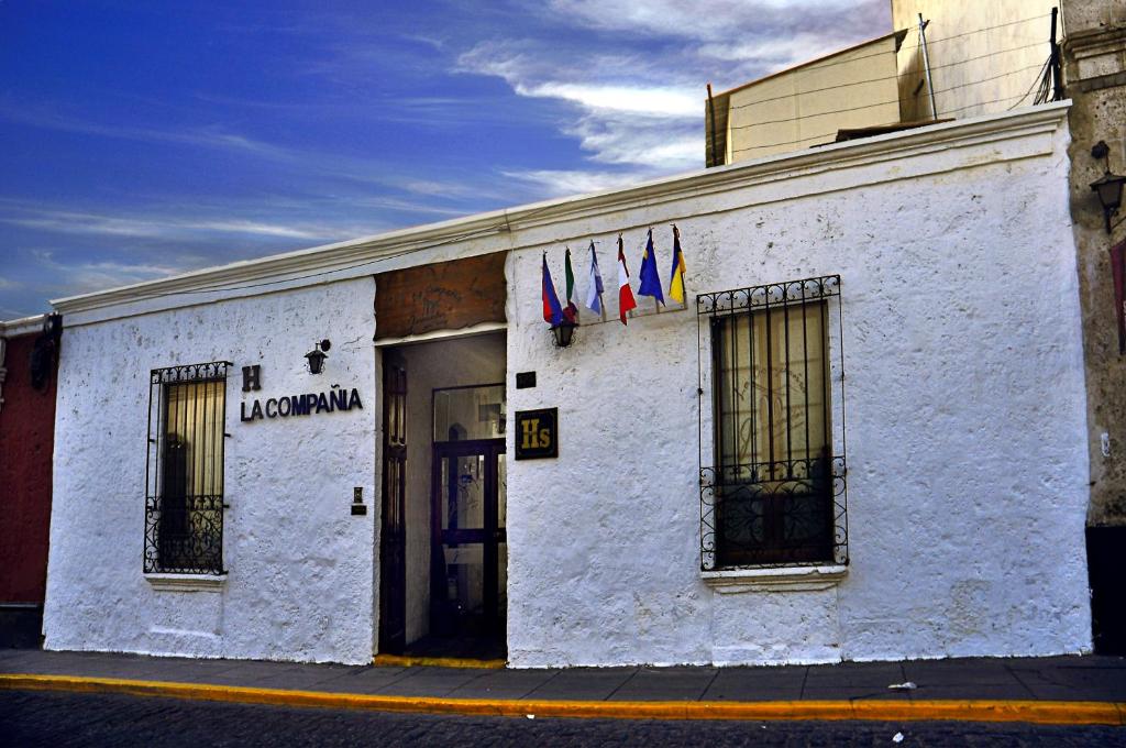 un edificio blanco con banderas a un lado en La Compañía de Jerusalen, en Arequipa