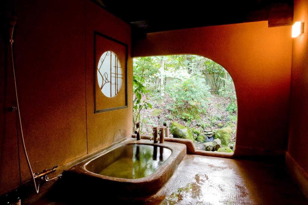 uma casa de banho com uma banheira e uma janela em Warabino em Yufu