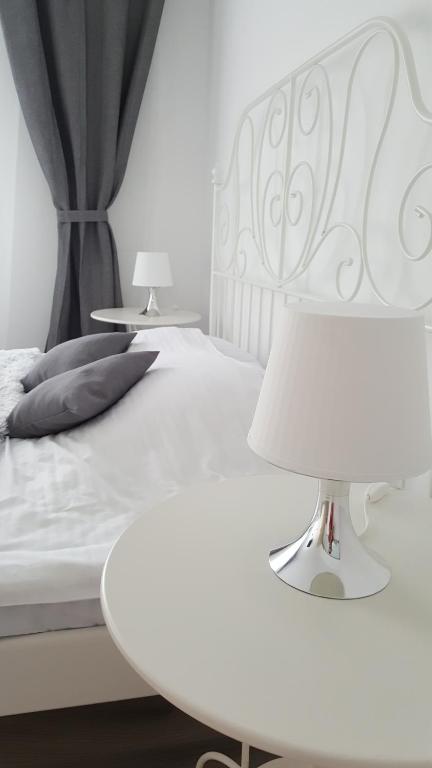 un letto bianco con testiera bianca e un tavolo con una lampada di Apart City Center a Braşov