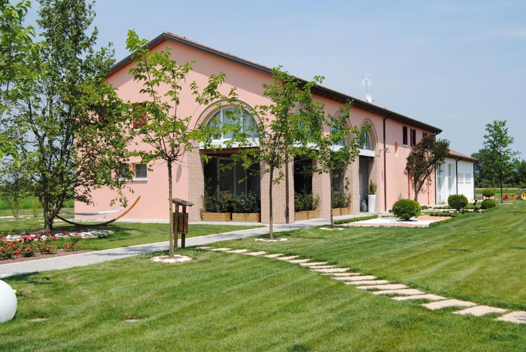 une maison rose avec une pelouse devant elle dans l'établissement Agriturismo Ca' Beatrice - Venice Airport, à Favaro Veneto