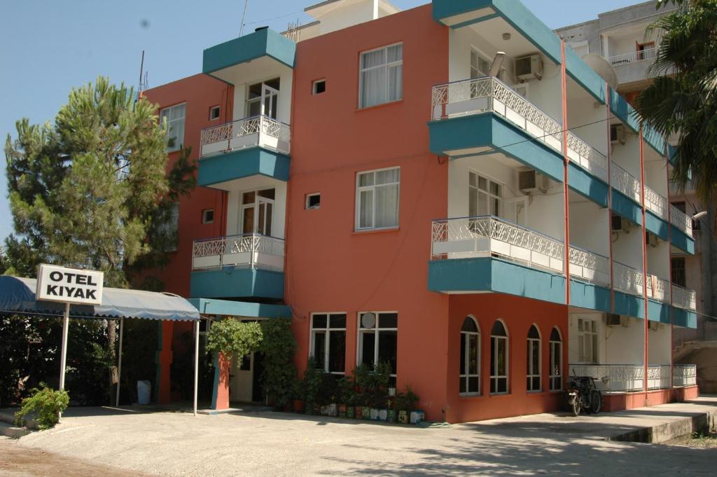 a red building with blue balconies and a sign at Kiyak Hotel in Demre