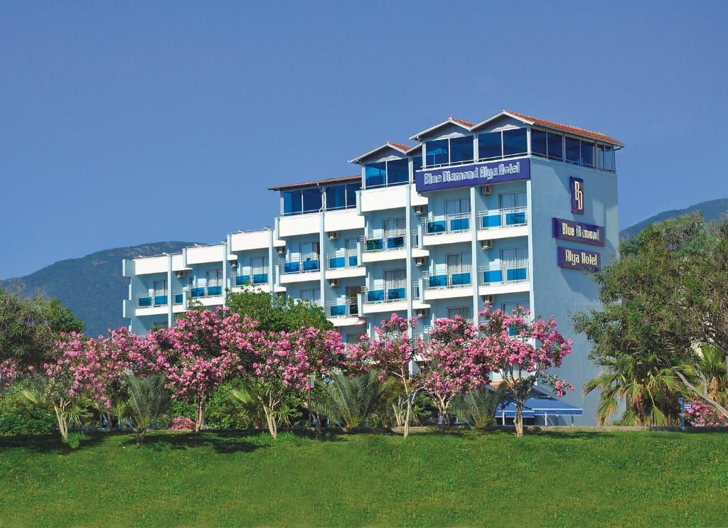 a large building with pink flowers in front of it at Blue Diamond Alya Hotel in Alanya