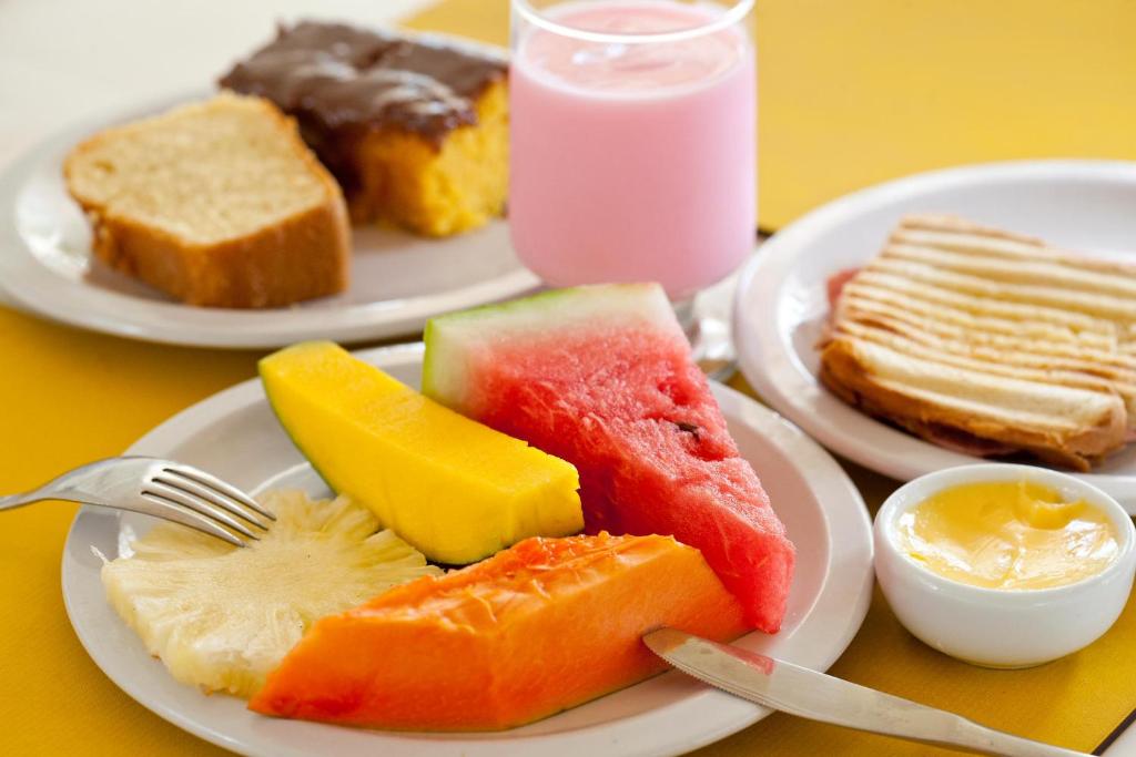 two plates of food with different types of fruit on a table at Pousada Barra Bonita in Barra de São Miguel