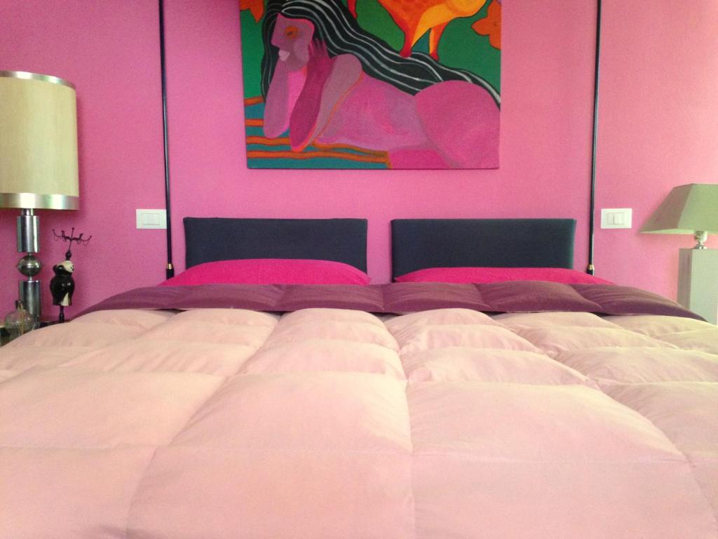 マリーナ・ディ・カッラーラにあるDomus Matilde relax beachのピンクの壁のベッドルーム1室(大型ベッド1台付)