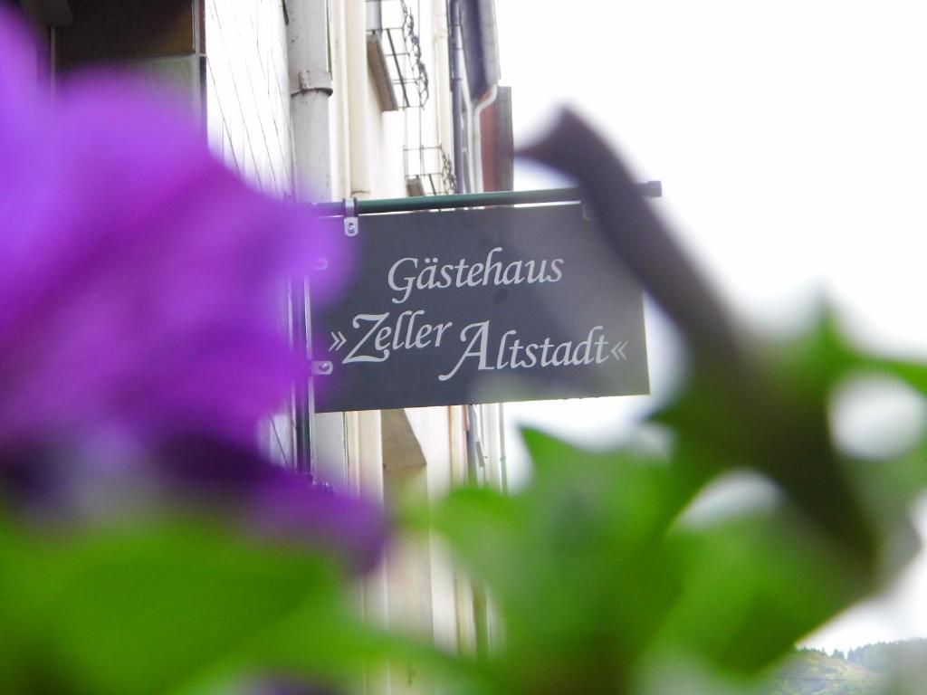 um sinal na lateral de um edifício com flores roxas em Gästehaus Zeller Altstadt em Zell an der Mosel