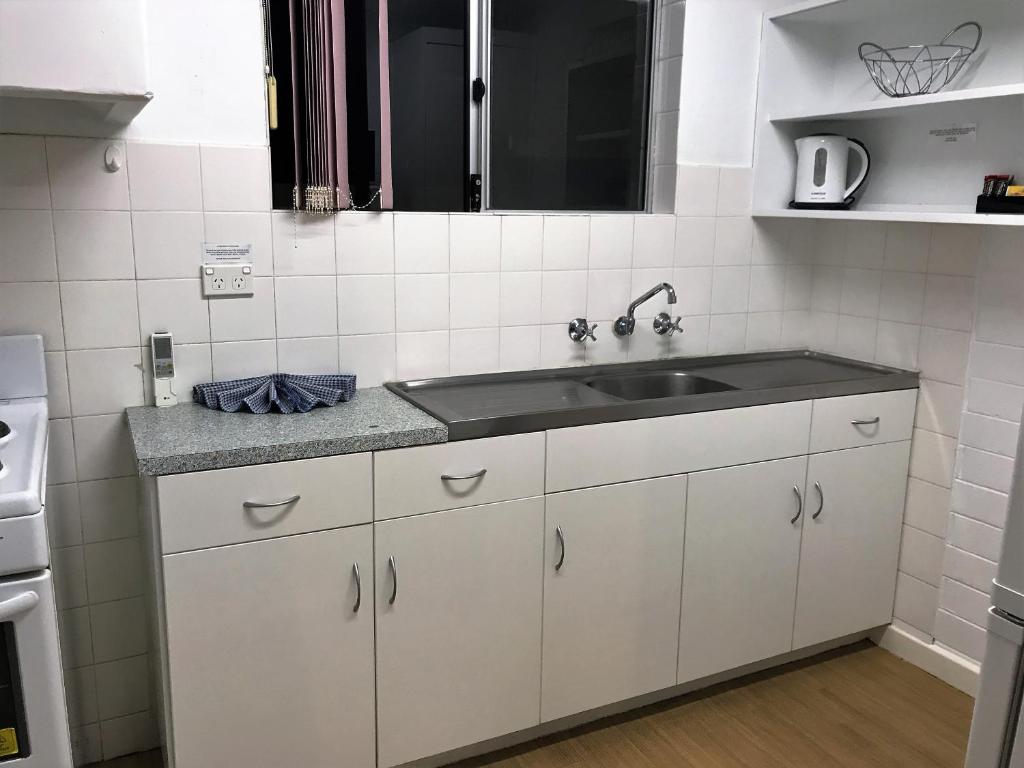 eine Küche mit weißen Schränken und einer Spüle in der Unterkunft Archipelago Apartments Esperance in Esperance