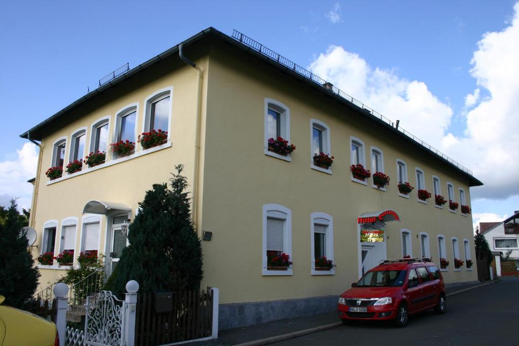 une voiture rouge garée devant un bâtiment jaune dans l'établissement Hotel "Alte Schule" Trogen, à Trogen