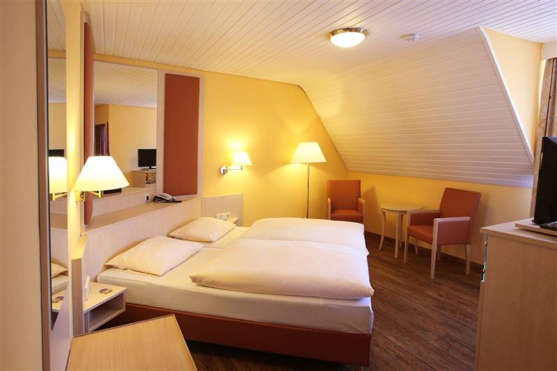 Cette chambre comprend un grand lit et une table. dans l'établissement Hotel Ritter, à Bruchsal