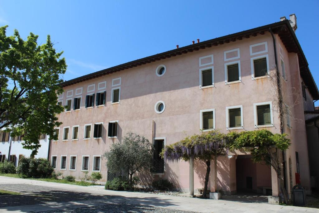 un gran edificio de ladrillo con un árbol delante de él en Ostello Europa, en San Vito al Tagliamento