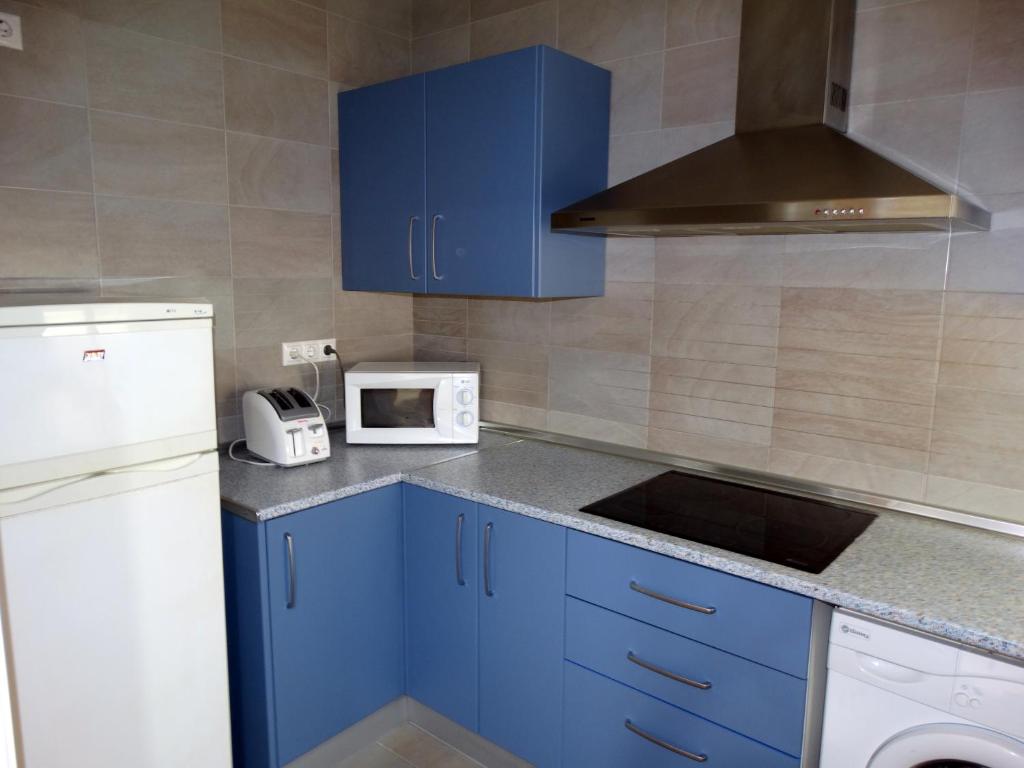 cocina con armarios azules y nevera blanca en Loft in the heart of Córdoba by gms apartamentos, en Córdoba