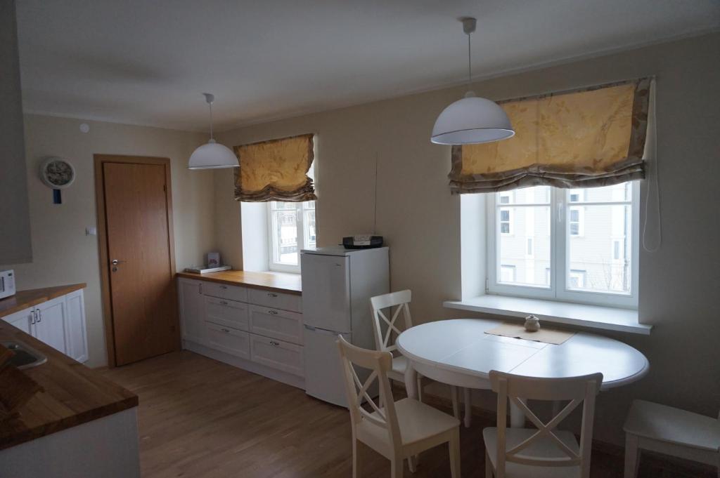a kitchen with a white table and chairs and two windows at Pargi Apartment in Kuressaare
