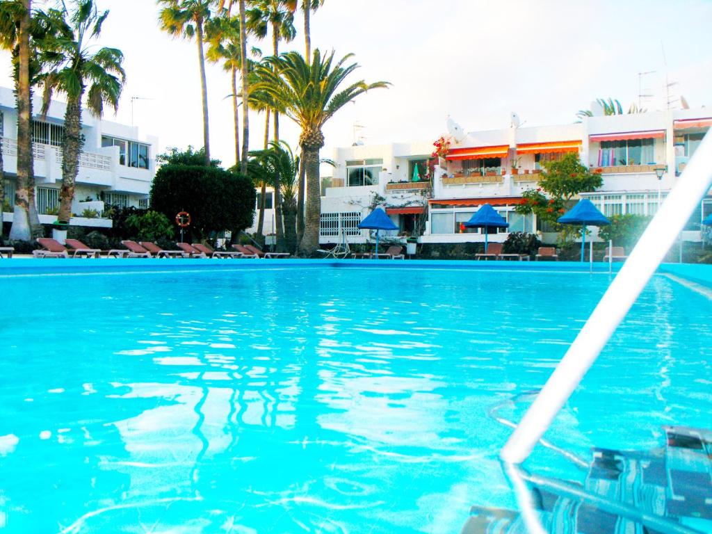 una piscina con palme e edifici sullo sfondo di Apartment Chaparral Complex a Costa Del Silencio