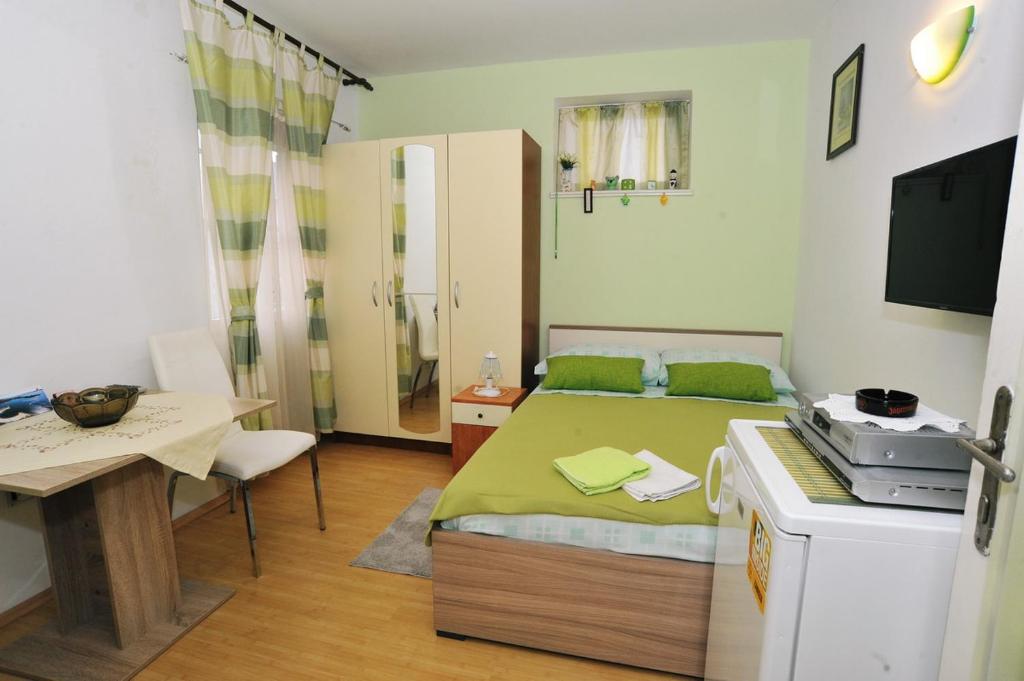 a small bedroom with a green bed and a table at Apartment Boris in Zadar
