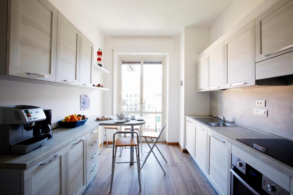 una cocina con armarios blancos y una mesa pequeña. en Riviera Apartments, en Levanto