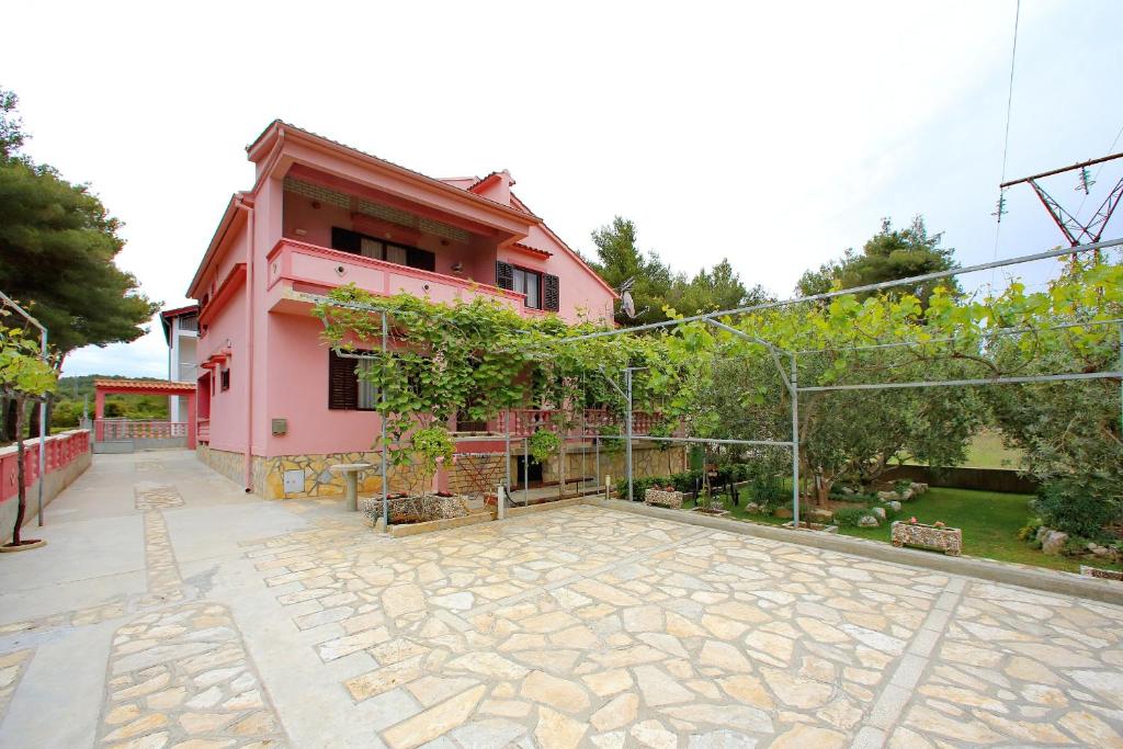 uma casa rosa com um pátio em frente em Apartmani Jagoda em Bibinje
